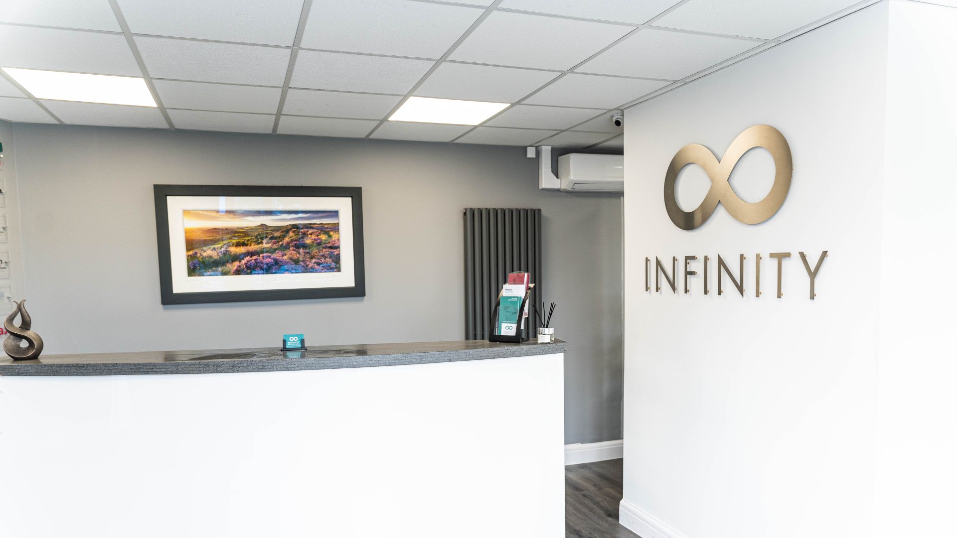 The infinity dental clinic reception desk and large logo on the wall